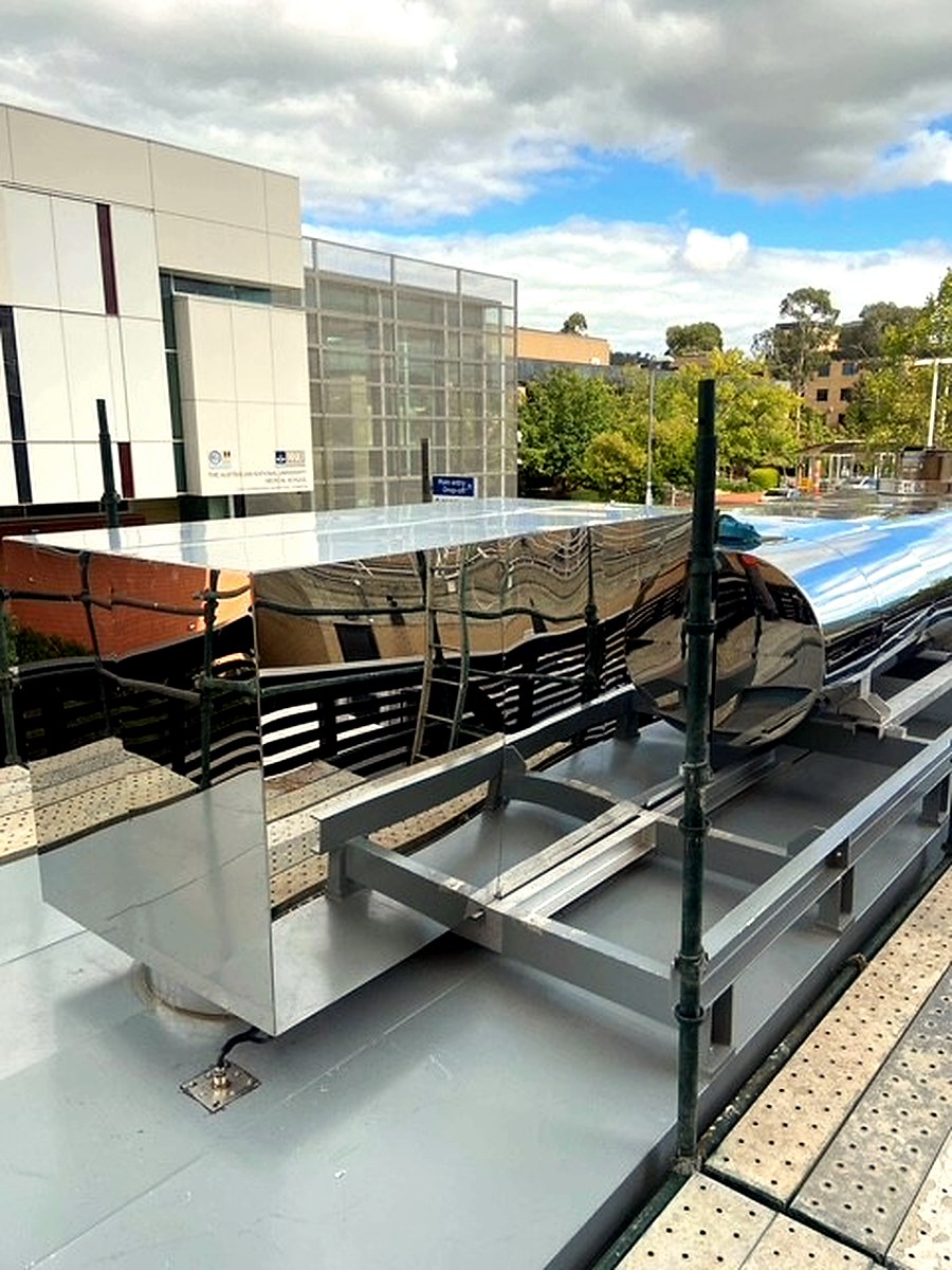 Polished stainless steel cladding on rooftop-mounted equipment with surrounding building visible